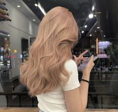 a woman with long red hair is looking at her cell phone while standing in front of a store window