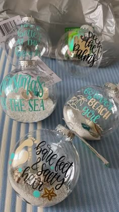 four glass ornaments with words on them sitting on top of a blue and white table cloth