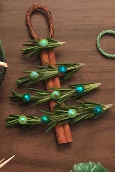 a small christmas tree made out of green beads and twine on a wooden table