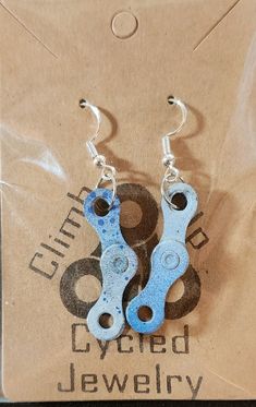 two pairs of blue bicycle chain earrings on a brown bag with the words cycled jewelry written below it