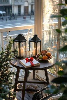 a table with fruit and candles on it in front of a window overlooking the street