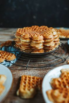 a stack of waffles sitting on top of a metal rack next to plates