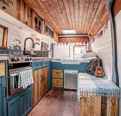 the interior of a tiny home with wood flooring and blue painted cabinets, including an oven