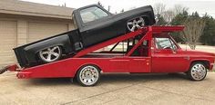 a red truck with two cars in the back and one car on the top bed