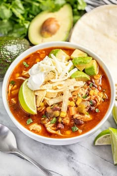 a bowl of chicken tortilla soup with avocado and cilantro