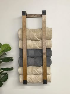 a stack of folded towels hanging on a wall next to a potted green plant