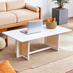 a living room with a couch, coffee table and laptop computer on top of it