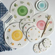 four woven coasters with different designs on them next to a fork and spoon rest