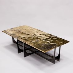 a table that is made out of metal and has a gold leaf design on it