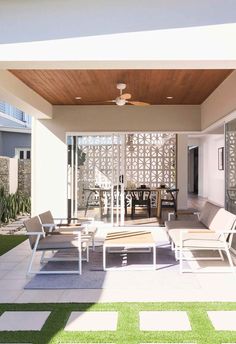 an outdoor living area with white furniture and green grass on the ground in front of it