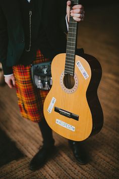 a man in kilt holding an acoustic guitar