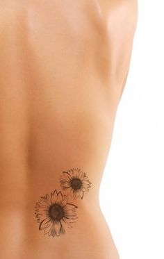 a woman's back with sunflower tattoos on her left side and the bottom part of her stomach