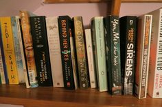 a row of books sitting on top of a wooden shelf