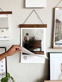 a person holding up a piece of paper in front of pictures and frames on the wall