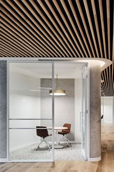 an office with wood slats on the ceiling and glass doors leading to another room