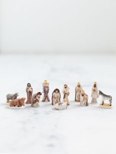 small figurines of people and animals on a white countertop with a gray background