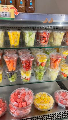 a display case filled with lots of different types of fruit and veggies in plastic cups