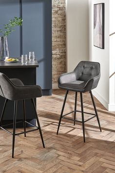 two bar stools sitting next to each other on top of a hard wood floor