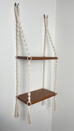 a wooden shelf with rope hanging from it's sides and two shelves on each side