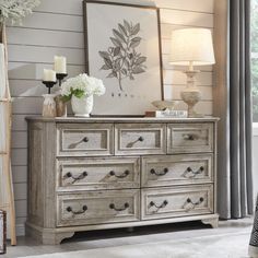 a white dresser with flowers and pictures on the wall