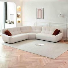 a white couch sitting on top of a hard wood floor next to a lamp and window