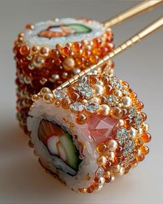 two sushi rolls covered in pearls and garnished with various colored stones, are sitting on a white surface