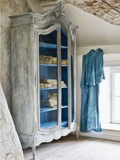 an old china cabinet with blue glass doors and drawers in a room next to a stone wall