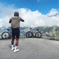 a man standing on top of a mountain next to two bikes