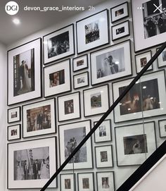 a staircase with many framed pictures on the wall next to an escalator and handrail