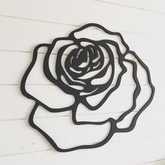 a metal rose is mounted on the side of a white wall with black trimmings