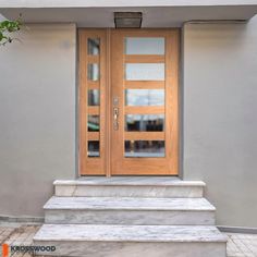 two wooden doors sitting next to each other on the side of a gray building with steps leading up to them