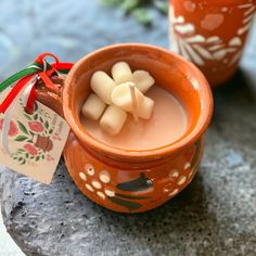 a small cup filled with liquid sitting on top of a stone table next to two vases