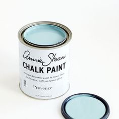 an open can of chalk paint next to a small black and white object on a white surface