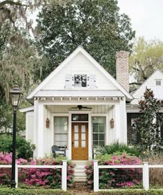 a white house with pink flowers in the front yard