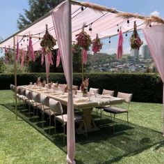 a table set up for a party with pink draping and hanging decorations on the ceiling