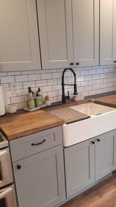 a kitchen with white cabinets and wooden counter tops, including a dishwasher in the center