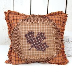 a plaid pillow with an embroidered leaf on it