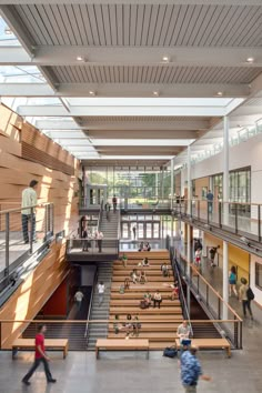 two people walking up and down the stairs in a large building with lots of windows