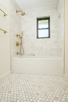 a white bathroom with hexagonal tile and gold fixtures