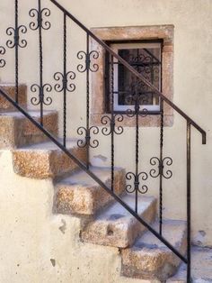 a set of stairs leading up to a window with wrought iron railings on each side