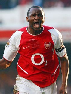 a soccer player with his mouth wide open and tongue out, running on the field