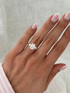 a woman's hand with pink manicured nails and an engagement ring