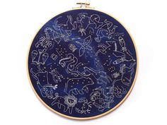 an embroidered blue and gold hoop with zodiac signs on it, sitting in front of a white background