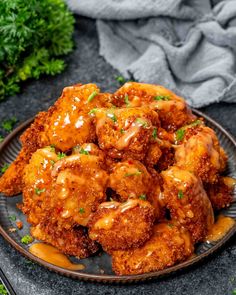 a plate filled with fried chicken covered in gravy and garnished with parsley