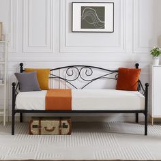 a white daybed with orange and grey pillows on it in a living room setting