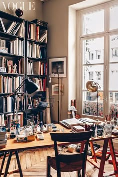 a room filled with lots of books next to a desk and chair in front of a window