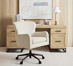 a white chair sitting in front of a desk with a painting on the wall behind it