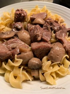 a white plate topped with pasta and meat