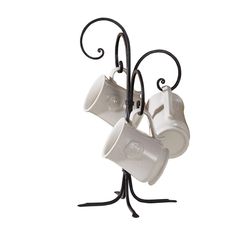 two coffee cups are hanging from a metal holder on a white background with black wrought iron stand