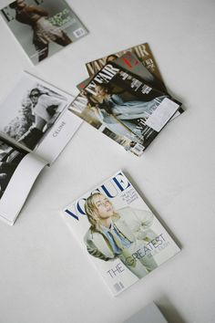 several magazines laying on top of a white table next to an open magazine with the cover pulled down